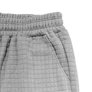 Präzise Detailansicht grauer Waffelstrick-Shorts mit elastischem Bund und Tasche.