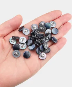 Detailed view of iridescent mother-of-pearl shirt buttons with metal shanks held in hand