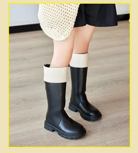 Detail view of kids black and white British style riding boots on a wooden floor
