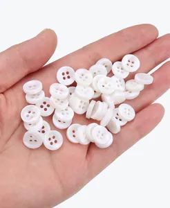 Nahaufnahme von natürlichen weißen Muschelknöpfen mit 4 Löchern in einer Hand