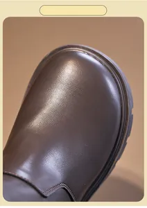 Close-up detail of children's brown leather Martin boot showing smooth toe texture.