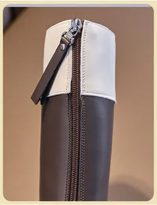 Close-up of durable metal back zipper on brown and cream leather children's boots