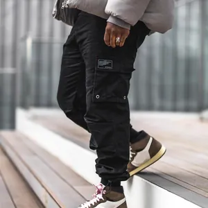 Détail du pantalon cargo noir pour homme avec poches multiples et chevilles serrées.