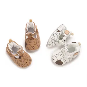 Detailed view of white and brown baby shoes featuring cute cartoon bear pattern prints