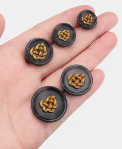 Detailed view of dark resin suit buttons with a golden braided heart decorative insert