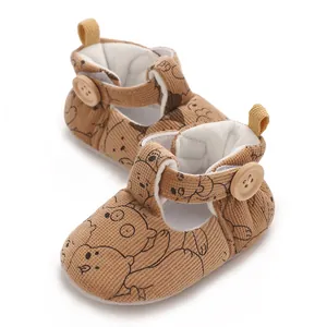Detailed view of brown corduroy baby shoes with cute cartoon bear print and button strap