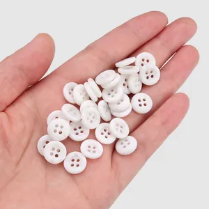 Hand holding eco-friendly white resin 4-hole buttons for cotton linen polo shirts