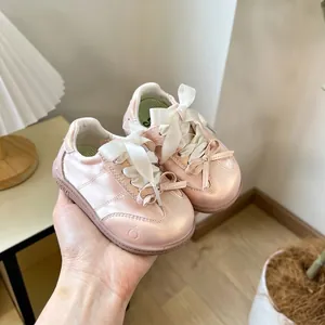 Gros plan de chaussures de marche rose satiné pour bébé avec d'élégants nœuds
