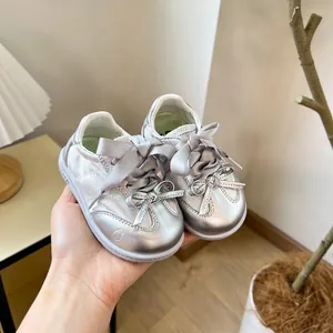 Vue détaillée de chaussures de marche argentées pour bébé avec un élégant nœud en satin souple