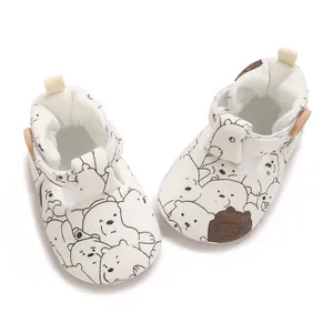 Close-up of white soft-soled baby shoes with cartoon bear pattern print