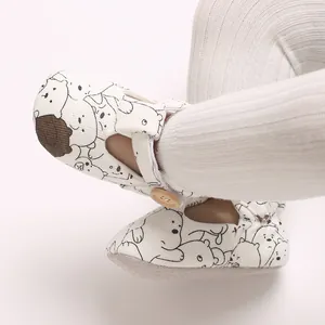Close-up of baby soft-sole walking shoes with cute cartoon bear pattern and button.