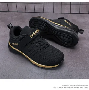 Close-up of black boys' fly-knit sports shoes with gold trim and velcro straps.