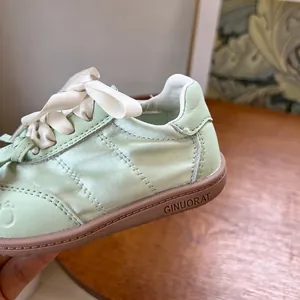 Détail en gros plan des baskets pour enfants vert menthe avec semelle souple marron classique