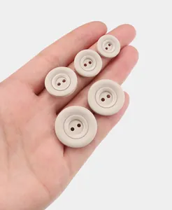 Beige matte Harzknöpfe in verschiedenen Größen in der Hand zum Größenvergleich