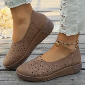 Vista detallada de mocasines marrones para mujer con patrón floral cortado a láser