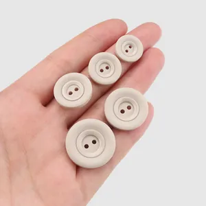 Umweltfreundliche beige Harzknöpfe in verschiedenen Größen zur Größenreferenz in der Hand