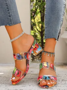 Close-up of colorful square gemstone patterns on clear straps of chunky heel sandals
