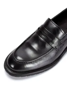 Detailopname van zwarte handgemaakte leren loafers met verfijnde textuur en stiksels.