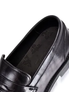 Gedetailleerde opname van leren herenloafers met focus op de binnenzool en textuur.