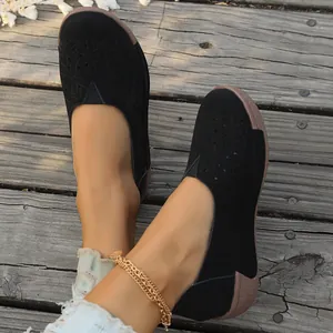 Comode scarpe basse nere da donna con motivo traforato su uno sfondo di passerella in legno