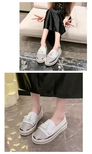 Detailed macro view of white platform loafers featuring rhinestone toes and stylish tassel accents