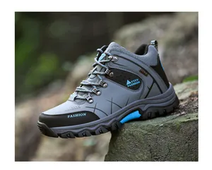 Detailed side view of grey and blue high-top hiking boots with rugged anti-slip soles outdoors