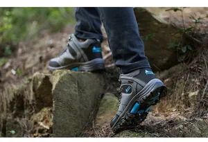 Close-up of durable high-top hiking boots on rocky terrain for outdoor trekking