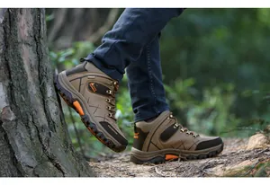 Side view of durable brown high-top hiking boots on an outdoor forest trail path