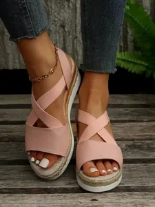 Détail de sandales compensées roses avec brides élastiques et semelles tressées.