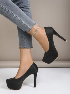 Close-up of black glitter platform pumps with 16cm stiletto heels on model