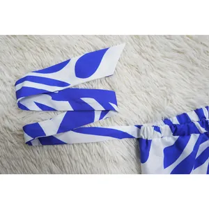 Detail view of blue and white printed jumpsuit waistband with tie-strap on white fur
