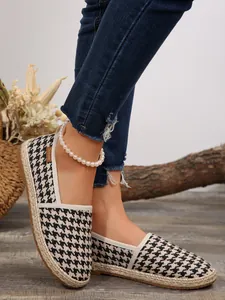 Nahaufnahme von lässigen Espadrilles für Damen mit Hahnentrittmuster und geflochtener Strohsohle.