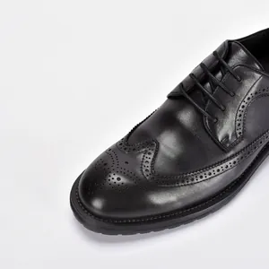 Close-up van zwarte leren brogue-schoenen met klassieke vleugeltip perforaties details
