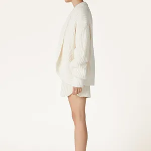 Femme élégante portant un ensemble gilet en grosse maille blanche et short assorti