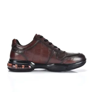Detail van bruine leren sneakers met krokodillenpatroon en zichtbare luchtkussenzool