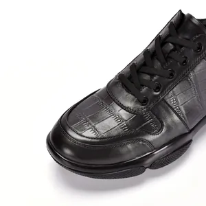 Macro detail van zwart leer met krokodillenreliëf op casual herensneakers van leer