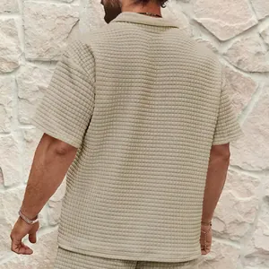 Λεπτομερής πίσω όψη ενός ανδρικού μπεζ πόλο με κομψή ανάγλυφη υφή βάφλας και κοντά μανίκια.