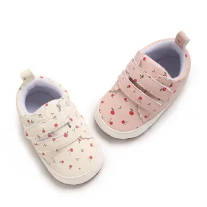 Nahaufnahme von Baby-Lernlaufschuhen mit Kirschmuster in Rosa und Cremeweiß
