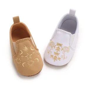 Detailansicht von Baby-Lauflernschuhen mit goldener Stickerei in Hellbraun und Weiß.