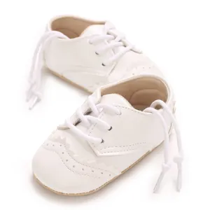 Vue détaillée de chaussures bébé en cuir PU blanc avec un design brogue élégant