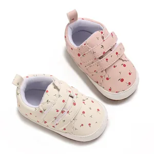 Detailaufnahme von rosa und cremefarbenen Baby-Lauflernschuhen mit Kirschmuster