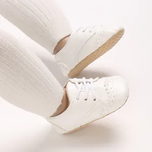 Détail de chaussures Oxford pour bébé garçon à semelle souple blanche avec broguing.