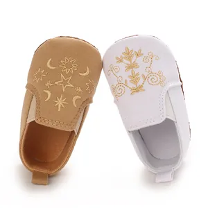 Nahaufnahme von Baby-Lauflernschuhen mit aufwendiger goldener Stern- und Mondstickerei