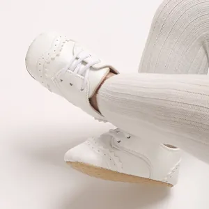Gros plan détaillé de chaussures pour bébé blanches style richelieu à semelles souples