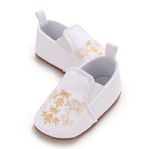 Detailansicht weißer Babyschuhe mit goldener Stickerei für die ersten Schritte