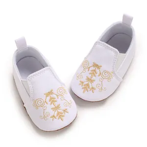 Detailaufnahme der weißen Baby-Lauflernschuhe mit feiner goldener Blumenstickerei auf Canvas