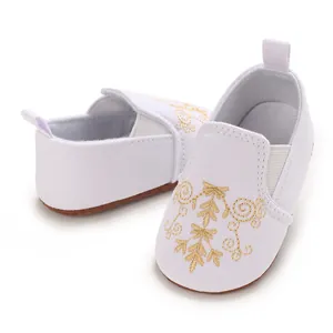 Nahaufnahme weißer Canvas-Lauflernschuhe für Babys mit goldener Blumenstickerei