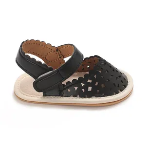 Vue détaillée d'une sandale noire pour bébé avec motif rétro évidé et élégants bords festonnés.