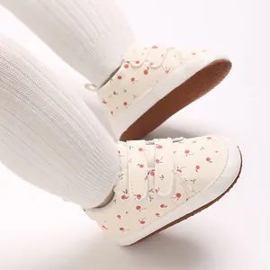 Detailaufnahme von Baby-Lauflernschuhen mit süßem Kirschmuster und weißem Klettverschluss.