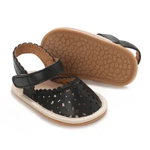 Détail de sandales noires pour bébé avec semelles souples antidérapantes tan.